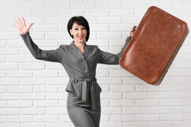 iş kadını çanta kalın beyaz bir duvar önünde bir gri takım elbise giymiş