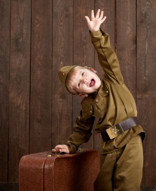 Çocuk Çocuk giymiş eski bavul, koyu ahşap arka plan, retro tarzı retro askeri üniformalı asker olarak