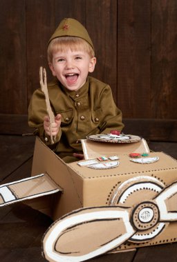 Çocuk Çocuk retro askeri üniformaları tamirde Polietilen, karton kutu, retro tarzı koyu ahşap arka plan bir uçak asker gibi giyinmiş