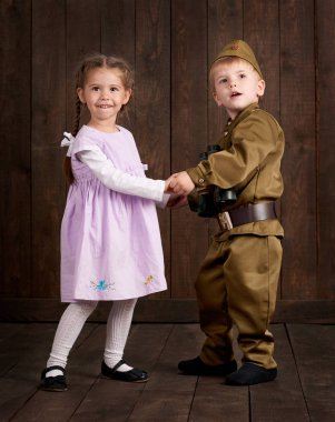 Çocuk Çocuk giyinmiş retro askeri üniformalı asker ve pembe elbiseli kız olarak