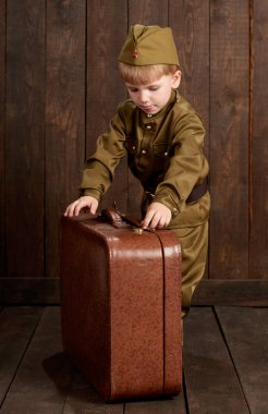 Çocuk Çocuk giymiş eski bavul, koyu ahşap arka plan, retro tarzı retro askeri üniformalı asker olarak