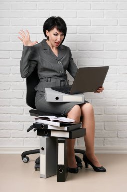 dizüstü bilgisayar ve klasörleri, iş kadın giyinmiş önünde beyaz bir duvar, bir gri takım teşkil etmektedir