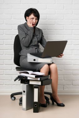 dizüstü bilgisayar ve klasörleri, iş kadın giyinmiş önünde beyaz bir duvar, bir gri takım teşkil etmektedir