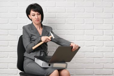 dizüstü bilgisayar ve stres, sahip klasörleri kızgın iş kadın giyinmiş önünde beyaz bir duvar, bir gri takım teşkil etmektedir