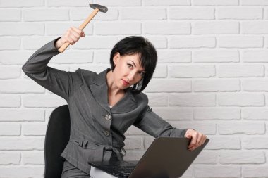 dizüstü bilgisayar ve stres, sahip klasörleri kızgın iş kadın giyinmiş önünde beyaz bir duvar, bir gri takım teşkil etmektedir