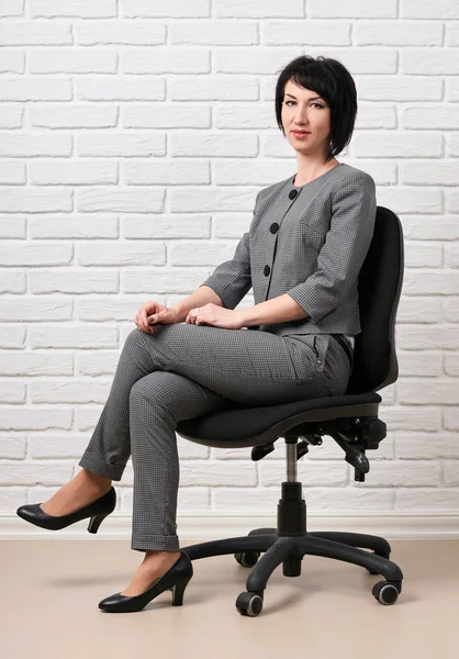 Biznes Kobieta Siedzi Krześle Ubrany Szary Garnitur Pozach Przodu Białej — Zdjęcie stockowe