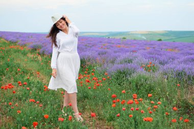 Genç kadın lavanta, güzel yaz manzara haşhaş kırmızı çiçekli alanındadır