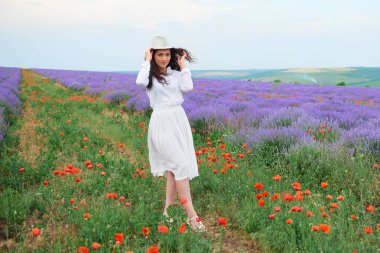 Genç kadın lavanta, güzel yaz manzara haşhaş kırmızı çiçekli alanındadır