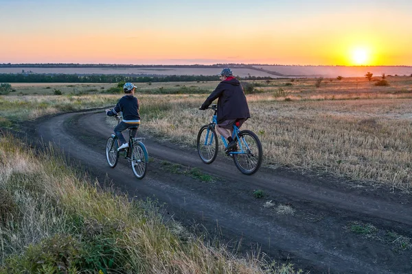 父と息子 夕方フィールド上国で自転車に乗る — ストック写真