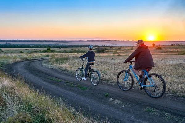 父と息子 夕方フィールド上国で自転車に乗る — ストック写真