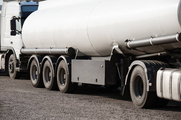 two white tank trucks on the road, clear and blank space on the cistern side