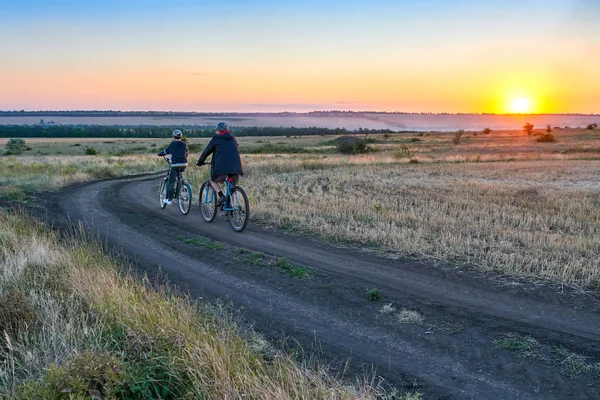 父と息子 夕方フィールド上国で自転車に乗る — ストック写真