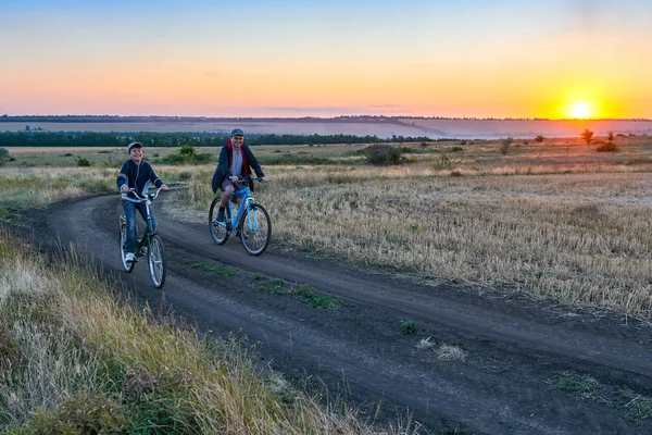 父と息子 夕方フィールド上国で自転車に乗る — ストック写真