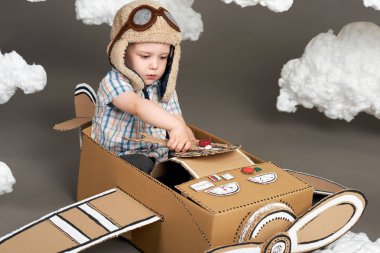 karton kutu ve bir pilot, gri bir arka plan, retro tarzı Pamuk yün bulutlar olma hayalleri yapılmış bir uçak çocuk oynar