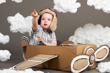 karton kutu ve bir pilot, gri bir arka plan, retro tarzı Pamuk yün bulutlar olma hayalleri yapılmış bir uçak çocuk oynar