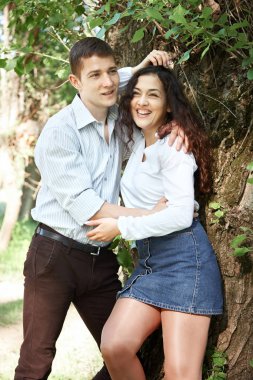 Genç çift, ormanda yürüyüş poz ağaç, yaz doğa, parlak güneş ışığı, gölgeler ve yeşil yaprakları, romantik duygular