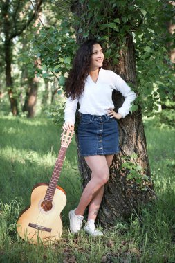 ormanda yürüyüş ve iskambil gitar, yaz doğa, parlak güneş ışığı, gölgeler ve yeşil yaprakları, romantik duygular genç kadın