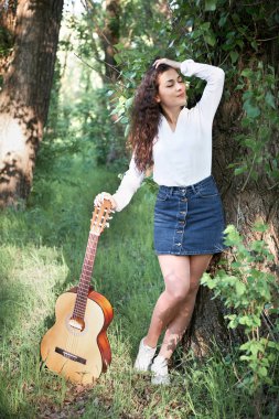 ormanda yürüyüş ve iskambil gitar, yaz doğa, parlak güneş ışığı, gölgeler ve yeşil yaprakları, romantik duygular genç kadın