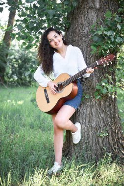 ormanda yürüyüş ve iskambil gitar, yaz doğa, parlak güneş ışığı, gölgeler ve yeşil yaprakları, romantik duygular genç kadın