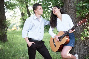 ormanda yürüyüş ve iskambil gitar, yaz doğa, parlak güneş ışığı genç çift, gölgeler ve yeşil yaprakları, romantik duygular