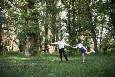ormanda yürüyüş ve iskambil gitar, yaz doğa, parlak güneş ışığı genç çift, gölgeler ve yeşil yaprakları, romantik duygular