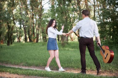 ormanda yürüyüş ve iskambil gitar, yaz doğa, parlak güneş ışığı genç çift, gölgeler ve yeşil yaprakları, romantik duygular