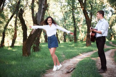 ormanda yürüyüş ve iskambil gitar, yaz doğa, parlak güneş ışığı genç çift, gölgeler ve yeşil yaprakları, romantik duygular