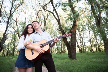ormanda yürüyüş ve iskambil gitar, yaz doğa, parlak güneş ışığı genç çift, gölgeler ve yeşil yaprakları, romantik duygular