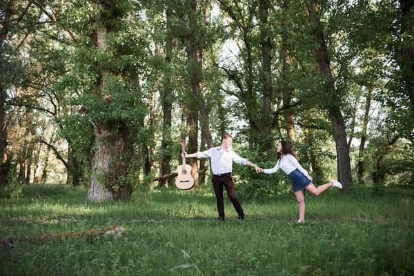 ormanda yürüyüş ve iskambil gitar, yaz doğa, parlak güneş ışığı genç çift, gölgeler ve yeşil yaprakları, romantik duygular
