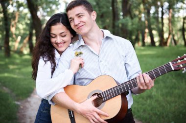 ormanda yürüyüş ve iskambil gitar, yaz doğa, parlak güneş ışığı genç çift, gölgeler ve yeşil yaprakları, romantik duygular