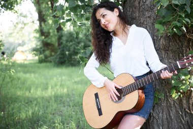 ormanda yürüyüş ve iskambil gitar, yaz doğa, parlak güneş ışığı, gölgeler ve yeşil yaprakları, romantik duygular genç kadın