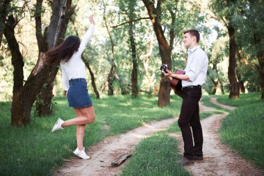 ormanda yürüyüş ve iskambil gitar, yaz doğa, parlak güneş ışığı genç çift, gölgeler ve yeşil yaprakları, romantik duygular