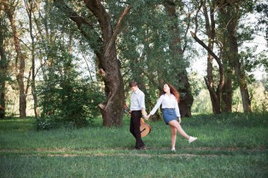 ormanda yürüyüş ve iskambil gitar, yaz doğa, parlak güneş ışığı genç çift, gölgeler ve yeşil yaprakları, romantik duygular