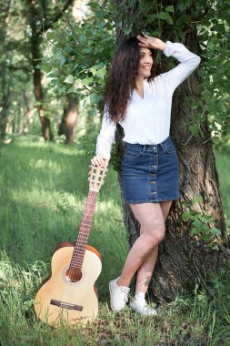 ormanda yürüyüş ve iskambil gitar, yaz doğa, parlak güneş ışığı, gölgeler ve yeşil yaprakları, romantik duygular genç kadın