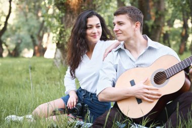 ormanda yürüyüş ve fotoğrafta eski fotoğraf makinesi, yaz doğa, parlak güneş ışığı, gitar, çalmak genç çift gölgeler ve yeşil yaprakları, romantik duygular