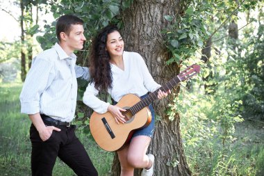 ormanda yürüyüş ve iskambil gitar, yaz doğa, parlak güneş ışığı genç çift, gölgeler ve yeşil yaprakları, romantik duygular