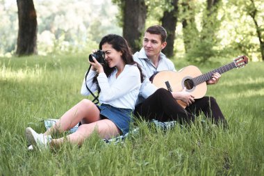 ormanda yürüyüş ve fotoğrafta eski fotoğraf makinesi, yaz doğa, parlak güneş ışığı, gitar, çalmak genç çift gölgeler ve yeşil yaprakları, romantik duygular