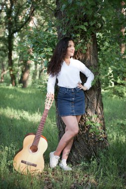 ormanda yürüyüş ve iskambil gitar, yaz doğa, parlak güneş ışığı, gölgeler ve yeşil yaprakları, romantik duygular genç kadın