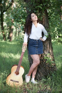 ormanda yürüyüş ve iskambil gitar, yaz doğa, parlak güneş ışığı, gölgeler ve yeşil yaprakları, romantik duygular genç kadın