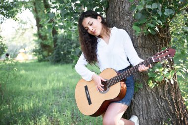 ormanda yürüyüş ve iskambil gitar, yaz doğa, parlak güneş ışığı, gölgeler ve yeşil yaprakları, romantik duygular genç kadın