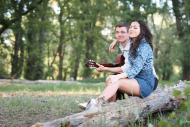 bir günlük ormanın içinde oturan ve iskambil gitar, yaz doğa, romantik duygular genç çift