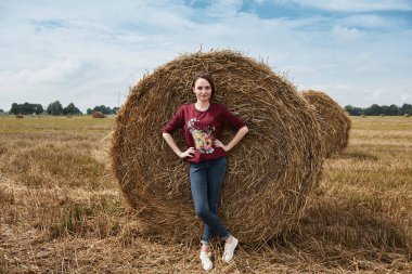 Genç kız alan, eğleniyor mowed saman bir haystack sarılmış