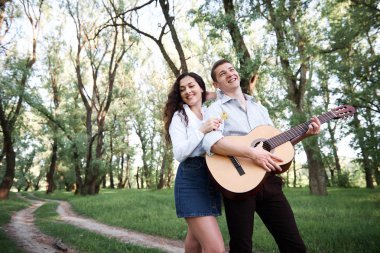 ormanda yürüyüş ve iskambil gitar, yaz doğa, parlak güneş ışığı genç çift, gölgeler ve yeşil yaprakları, romantik duygular
