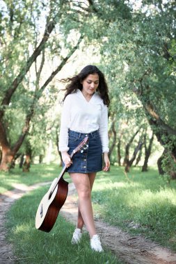 ormanda yürüyüş ve iskambil gitar, yaz doğa, parlak güneş ışığı, gölgeler ve yeşil yaprakları, romantik duygular genç kadın