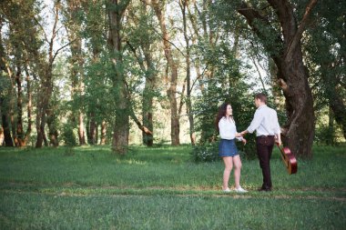 ormanda yürüyüş ve iskambil gitar, yaz doğa, parlak güneş ışığı genç çift, gölgeler ve yeşil yaprakları, romantik duygular