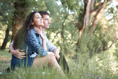 Genç çift, orman ve günbatımı, yaz doğa, parlak güneş ışığı arıyor çimlerde oturan gölgeler ve yeşil yaprakları, romantik duygular