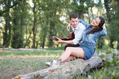 bir günlük ormanın içinde oturan ve iskambil gitar, yaz doğa, romantik duygular genç çift