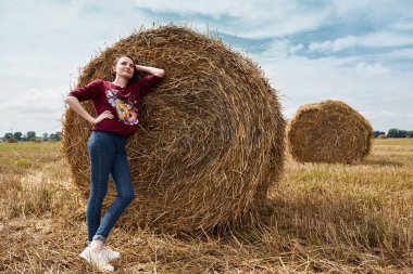 Genç kız alan, eğleniyor mowed saman bir haystack sarılmış