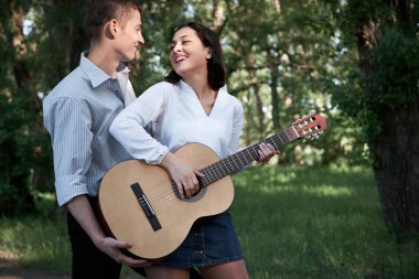 Genç çift, ormanda yürüyüş gitar çalmak ve dans, yaz doğa, parlak güneş ışığı, gölgeler ve yeşil yaprakları, romantik duygular