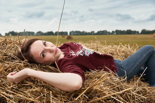 Genç kız eğleniyor alanında bir haystack yalan